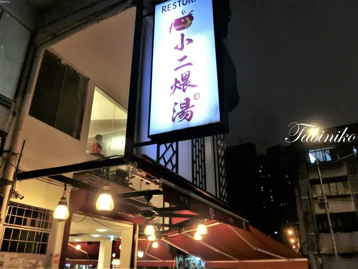 夜間に照らされた「小二煨湯」の縦型看板。中国語の文字と魚のロゴが特徴です。