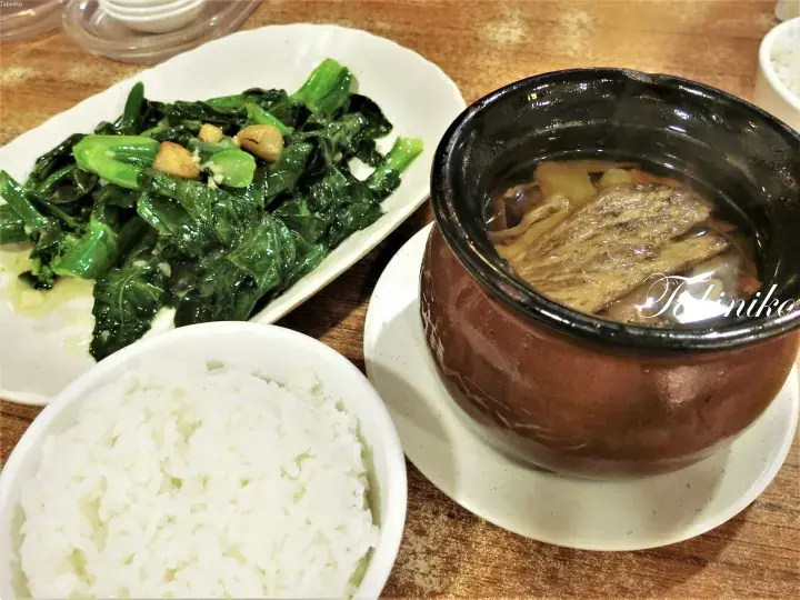木製テーブルに置かれたハーブスープの土鍋、ご飯、炒め野菜