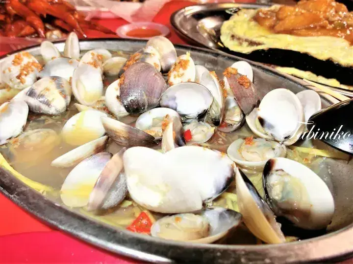 A sizzling platter of steamed clams with garlic and chili, served at a Malaysian seafood restaurant.