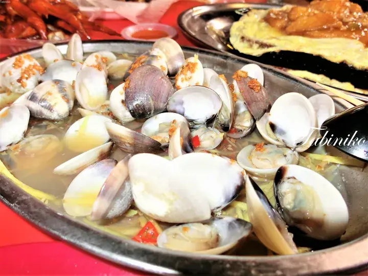 マレーシアの海鮮レストランで提供される、ニンニクと唐辛子を添えた蒸し蛤の鉄板料理。