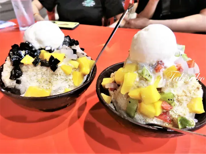 マンゴー、キウイ、ゼリー、バニラアイスクリームをトッピングした二つのシロップかけ氷。