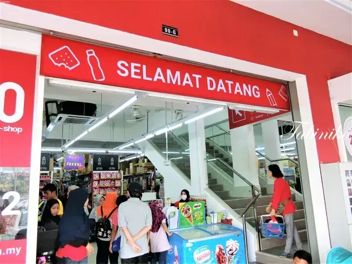 Customers enter a convenience store with a red “SELAMAT DATANG” sign above the entrance.