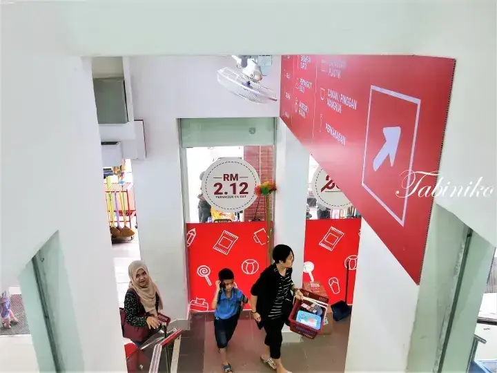 Visitors enter a venue with red signage showing RM 2.12 pricing and a Tabiniko watermark.