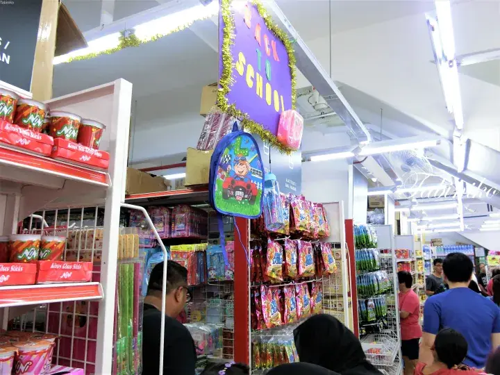 マレーシアの店舗で、子供用のバックパックや「Back to School」の看板が目立つ学用品のディスプレイ。