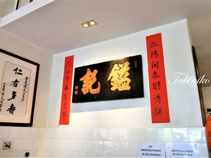 马来西亚餐厅白墙上悬挂的传统中国书法匾额和对联。