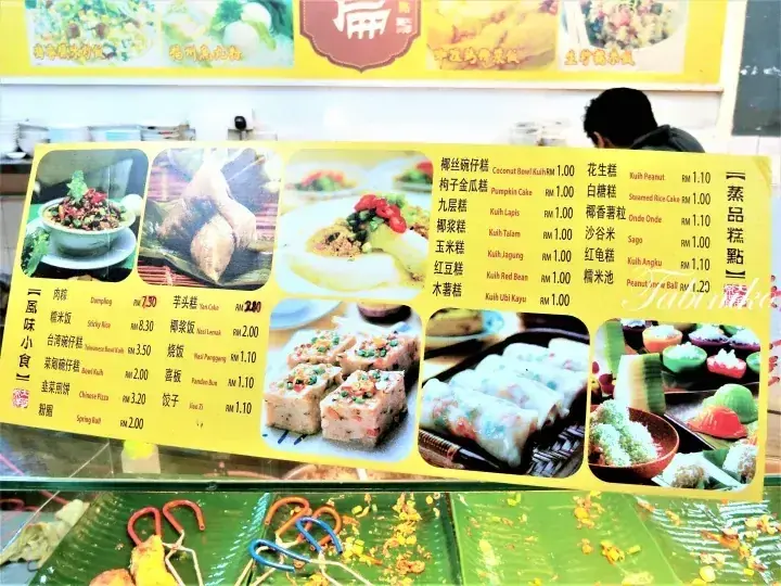 Yellow menu board displaying various Malaysian snacks and desserts with prices in Ringgit, featuring images of dishes like kuih and dim sum.