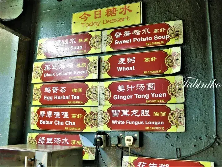 A menu board displaying various traditional Malaysian desserts like Sweet Potato Soup and Ginger Tong Yuen with prices.