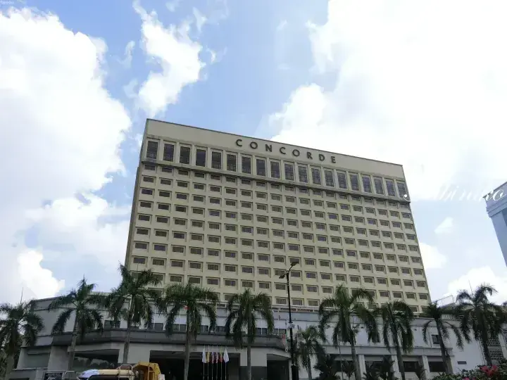 Concorde hotel building with palm trees under a blue sky