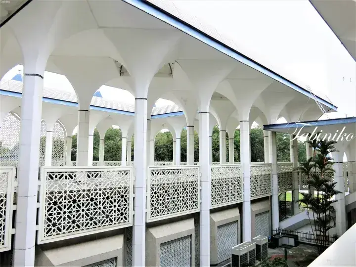 White arches and geometric lattice railings at a modern mosque in Malaysia, showcasing Islamic architectural details.