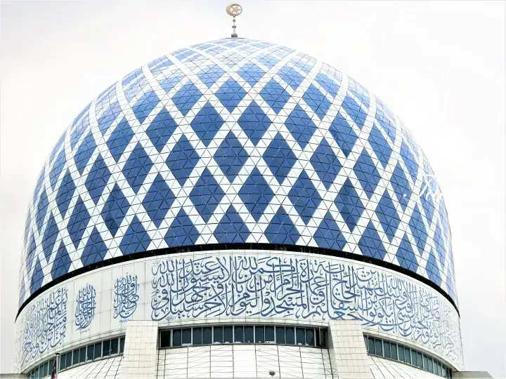 Blue and white geometric dome of the National Mosque featuring Arabic calligraphy and a crescent finial.