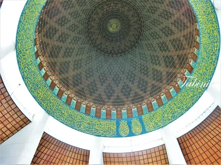 Intricate geometric dome ceiling with Arabic calligraphy and stained glass at the National Mosque in Kuala Lumpur