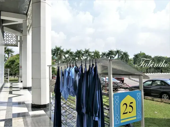 Blue and navy shirts hanging on a drying rack outside a modern building with a sign showing number 25.