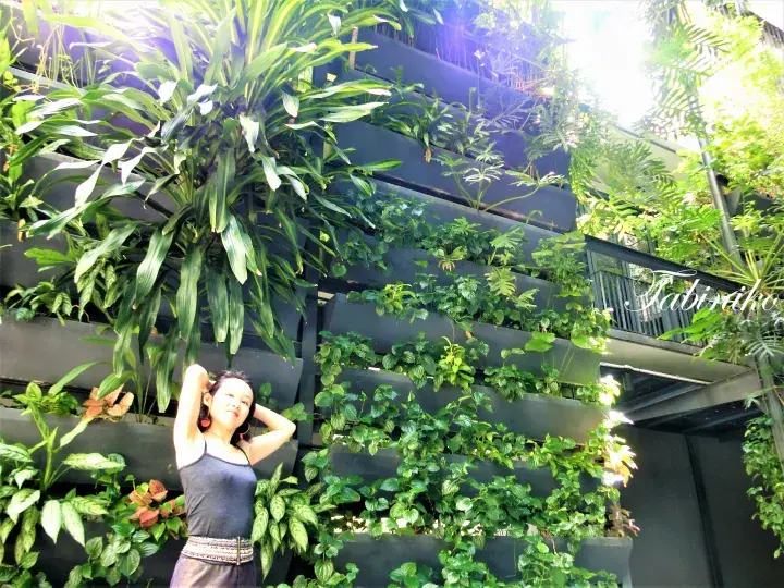 A woman stands in front of a lush vertical garden wall at Labyrinth Hotel in Kuala Lumpur.