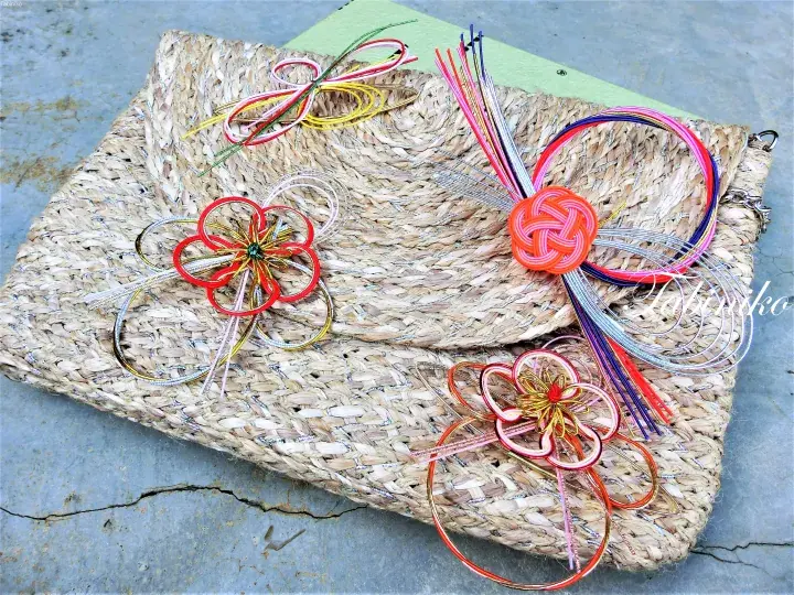 Colorful handmade kumihimo hair accessories displayed on a woven straw mat.
