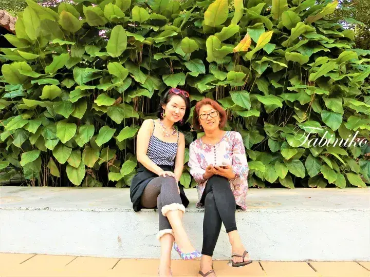 两位女士坐在马来西亚塔比尼科（Tabiniko）郁郁葱葱的绿植前。