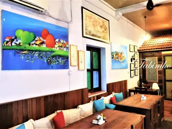 Cozy interior of Tabiniho cafe featuring colorful wall art, wooden furniture, and cushioned seating.