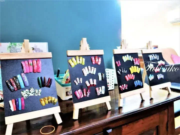 Colorful press-on nail samples displayed on small wooden easels at a beauty salon counter.