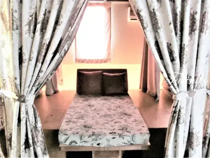Cozy bed with floral bedding and two pillows framed by elegant patterned curtains in a hotel room.