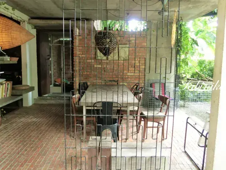Dining area with brick walls and a wire mesh partition, viewed through a metal gate.
