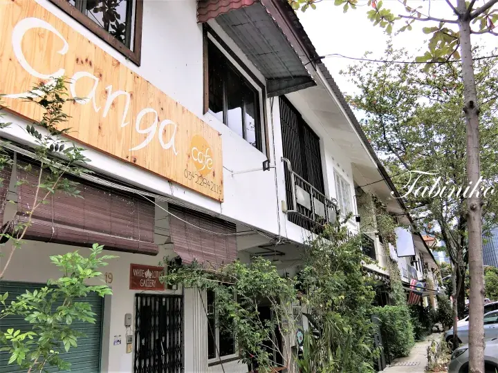 マレーシアの街並みにあるGanga Cafeの外観と木製看板、緑豊かな植栽