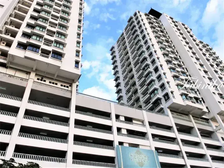 Low-angle view of Heritage at V Hotel towers and parking structure against a blue sky