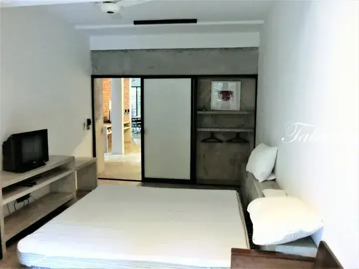 Modern bedroom with a white mattress, concrete accent wall, and sliding glass doors leading to an outdoor area.