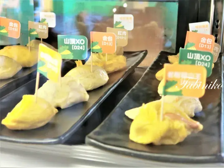 冷蔵ケースに並べられたD24やD13など、ラベル付きの様々な種類のドリアン果肉。