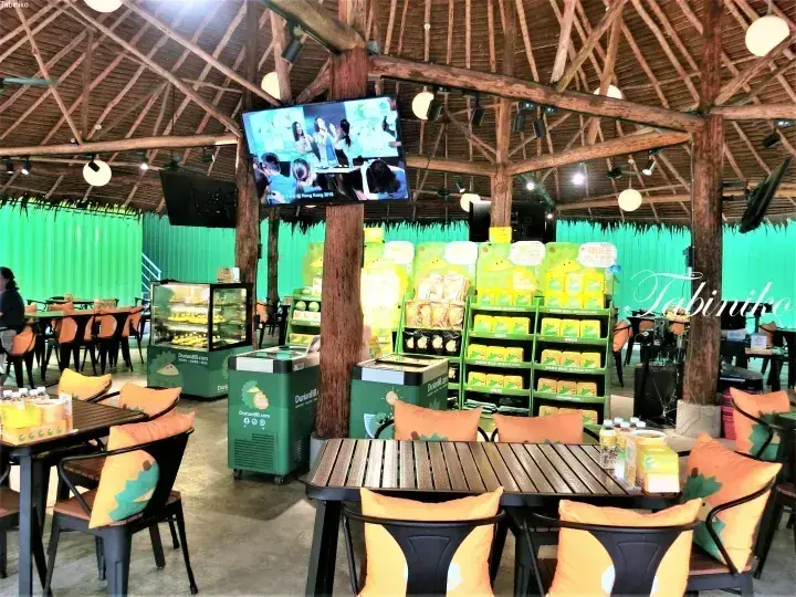DurianBB outlet interior with wooden beams, green walls, and shelves stocked with Musang King durian products.