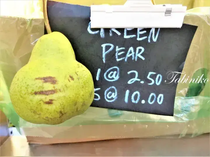 A green pear next to a chalkboard sign displaying prices for 1 at 2.50 and 5 at 10.00.