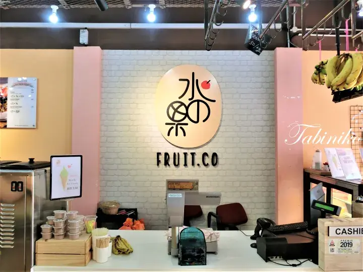 白いレンガ壁と丸いロゴが特徴的なFruit Co.の店舗内装。