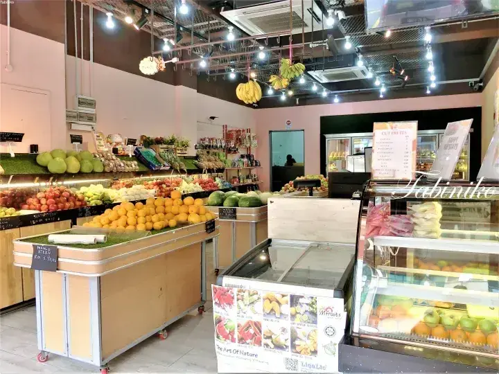 Interior of Mfruits shop displaying fresh produce like pomelos, oranges, and bananas hanging from the ceiling.