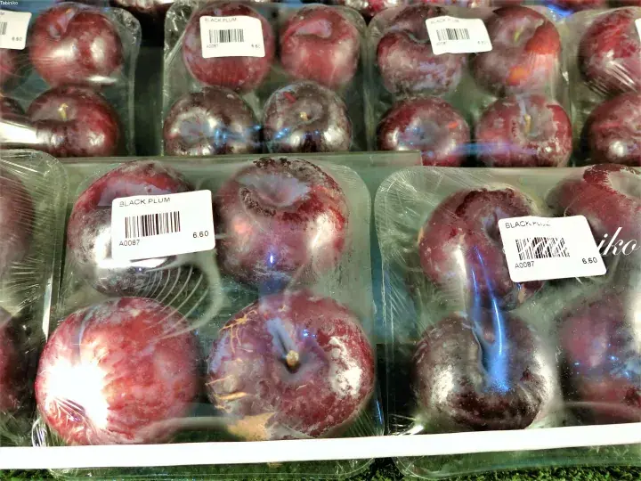 価格6.60のラベルが貼られた「BLACK PLUM」のブラックプラムがプラスチック容器に詰められ、店頭に並んでいる。