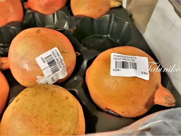 Fresh pomegranates from India in a black plastic tray with price stickers showing 5.50.