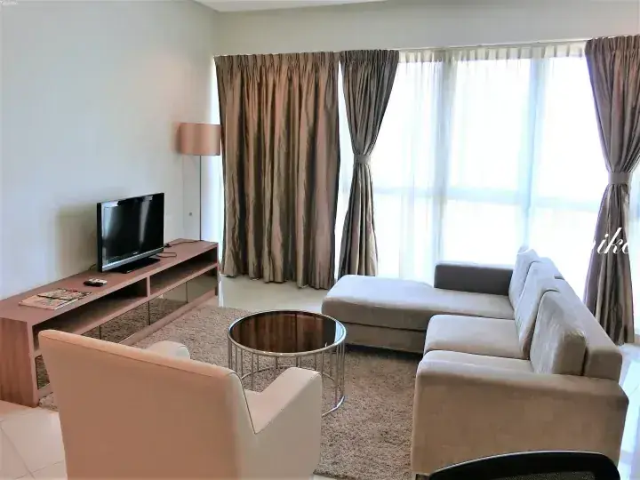 Bright living room with beige sofa, TV, and large window in a Malaysia serviced residence.