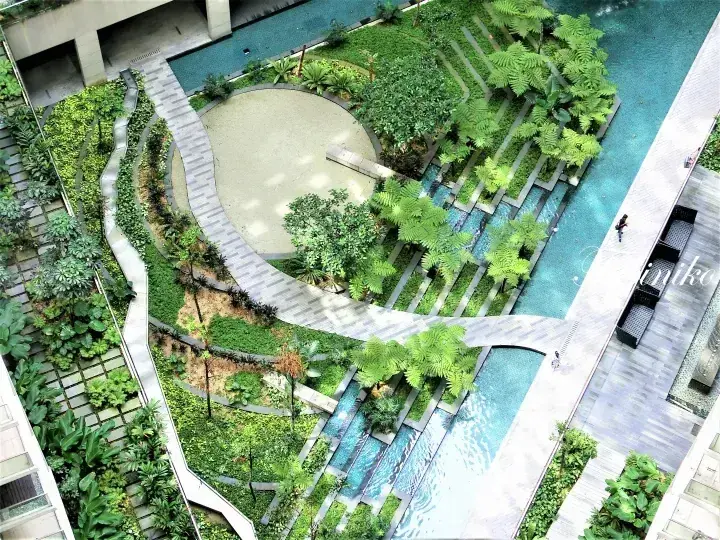 Aerial view of lush tropical gardens and swimming pools at a modern Malaysian residential property.