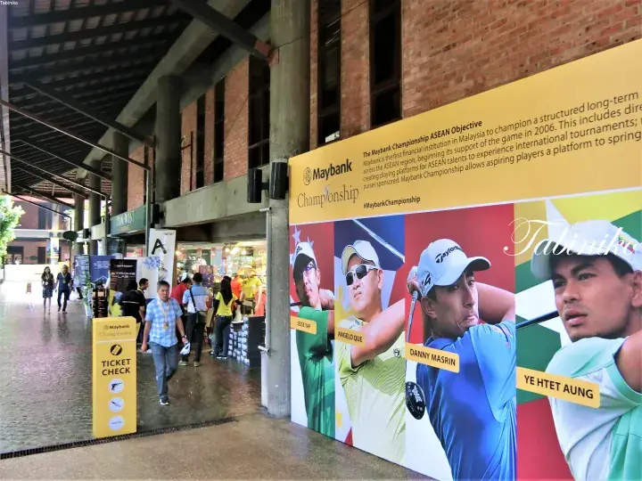 Entrance to Maybank Championship golf event with large promotional banner featuring players and ticket check signage.