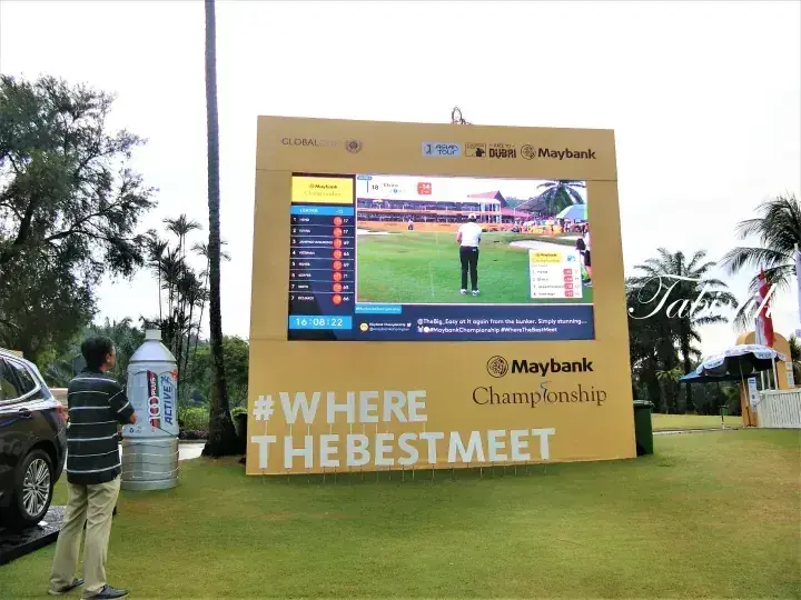 緑豊かなコースに設置された大型Maybank Championshipスコアボード。ライブのゴルフ映像とスコアを表示している。