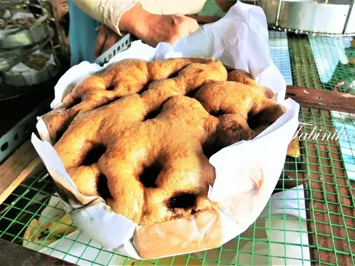 Freshly steamed, golden-brown Malaysian kuih with a spongy texture, served on a green wire rack.