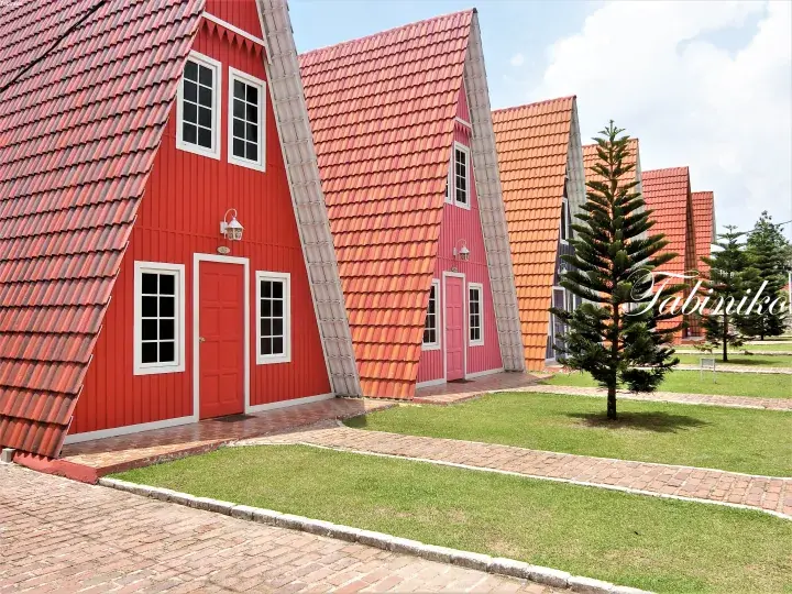 Colorful A-frame houses with red and pink facades and tiled roofs at a property in Malaysia.