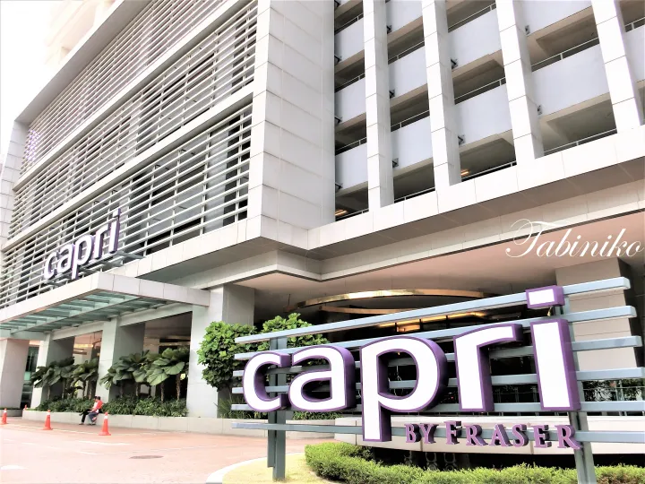 Capri by Fraser hotel entrance with purple signage and modern white facade