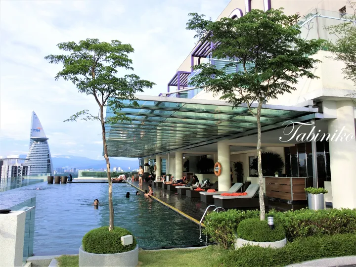 Infinity pool at a rooftop terrace with lounge chairs, overlooking the TM Tower in Kuala Lumpur.