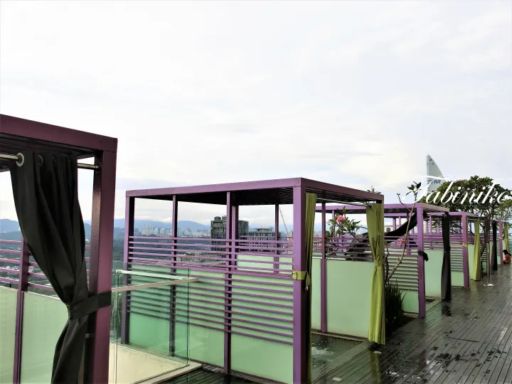 Purple cabanas with curtains on a rooftop deck overlooking Kuala Lumpur skyline and distant mountains