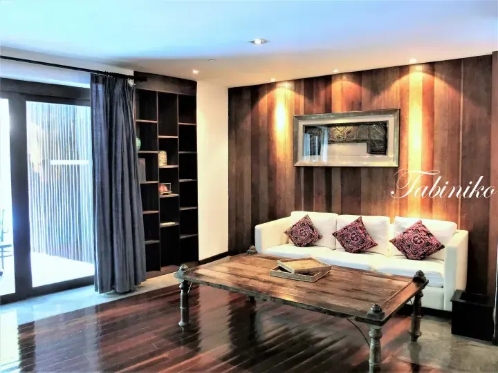Modern living room with white sofa, wooden coffee table, and dark wood paneling at a luxury property.