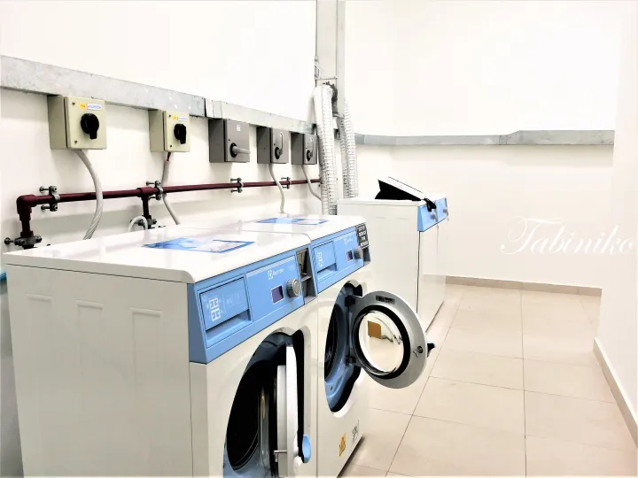 壁面コンセントと配管を備えた清潔なランドリールームのElectrolux洗濯機。