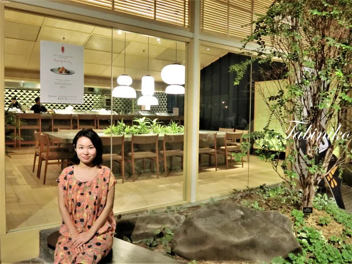 ザ・スターリングス・クアラルンプールのレストランBotanicaの外で、花柄のドレスを着た女性が座っている。