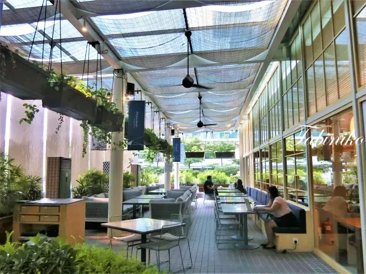 Modern outdoor dining area with hanging plants and shade netting at a property