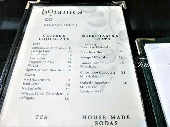 Menu from botanica + CO Bangsar South listing coffee, chocolate, milkshakes, and sodas with prices.