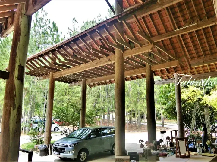 Silver Toyota Innova parked under a wooden pergola at a resort in Malaysia surrounded by pine trees