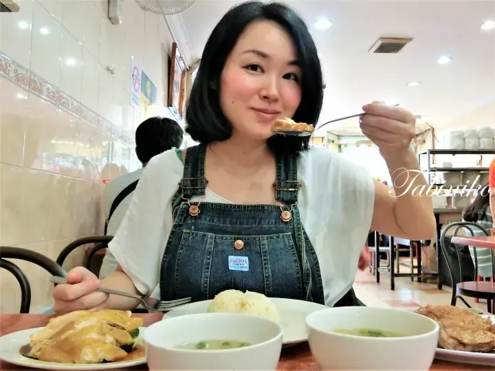 Woman eating Hainanese chicken rice at a restaurant in Malaysia