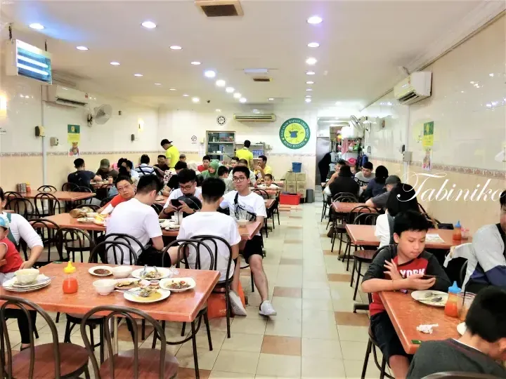 Busy dining room at Nasi Ayam Hainan Chee Meng Bukit Bintang with patrons eating at tables.